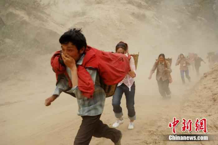 2008年5月20日,汶川震区民众快速通过山体滑坡险段。中新社记者 陈文 摄  汶川地震十二年:遥忆悲伤,记住灾难中不屈的精神