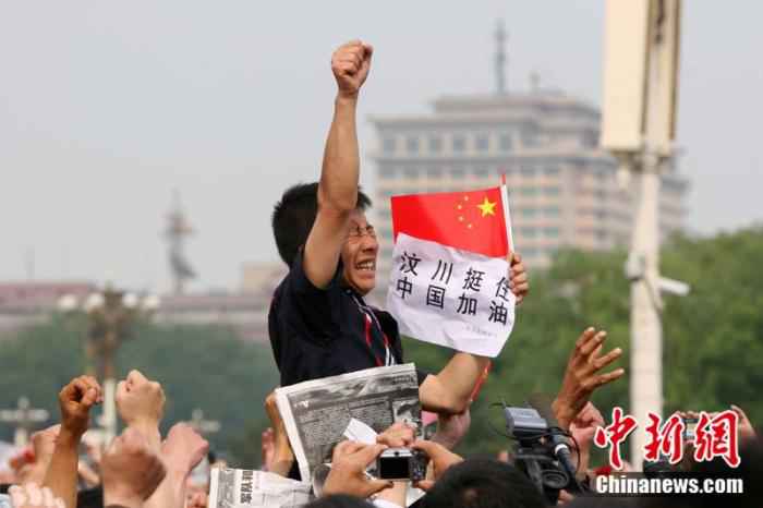 2008年5月19日,北京天安门广场上的民众为地震遇难者默哀,一位来自四川的男子高举右手为家乡加油。中新社记者 富田 摄  汶川地震十二年:遥忆悲伤,记住灾难中不屈的精神